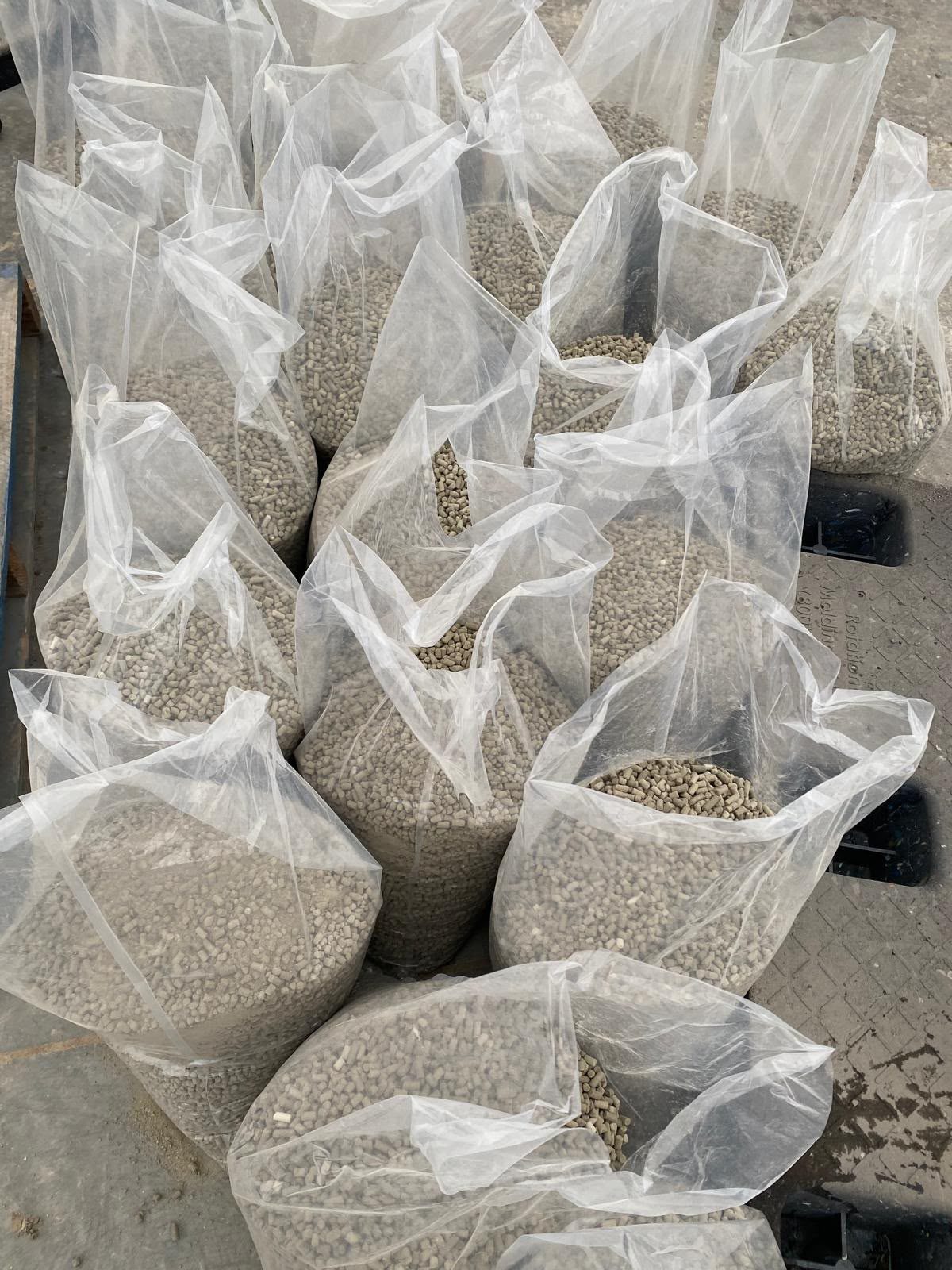 Open clear bags filled with grey mineral pellets