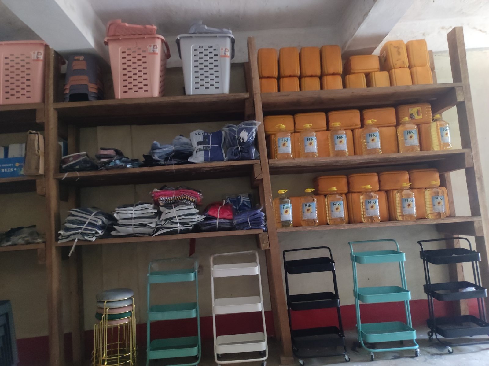 Shelves of cooking oil, jerrycans, clothing, and household carts
