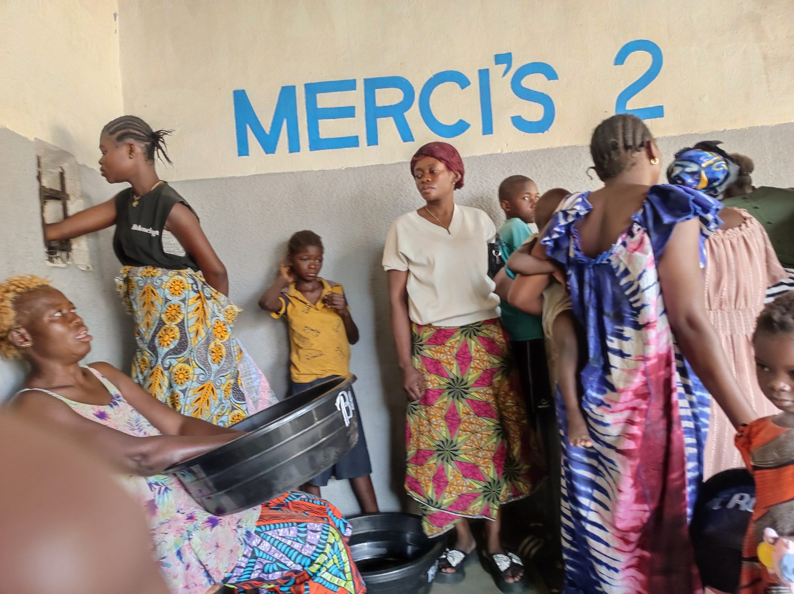 Women and children at a shop painted Merci's 2