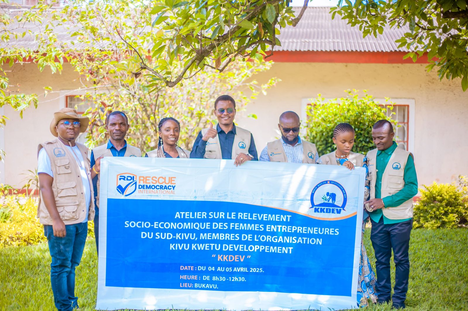 A team holding an RDI and KKDEV banner outdoors in Bukavu