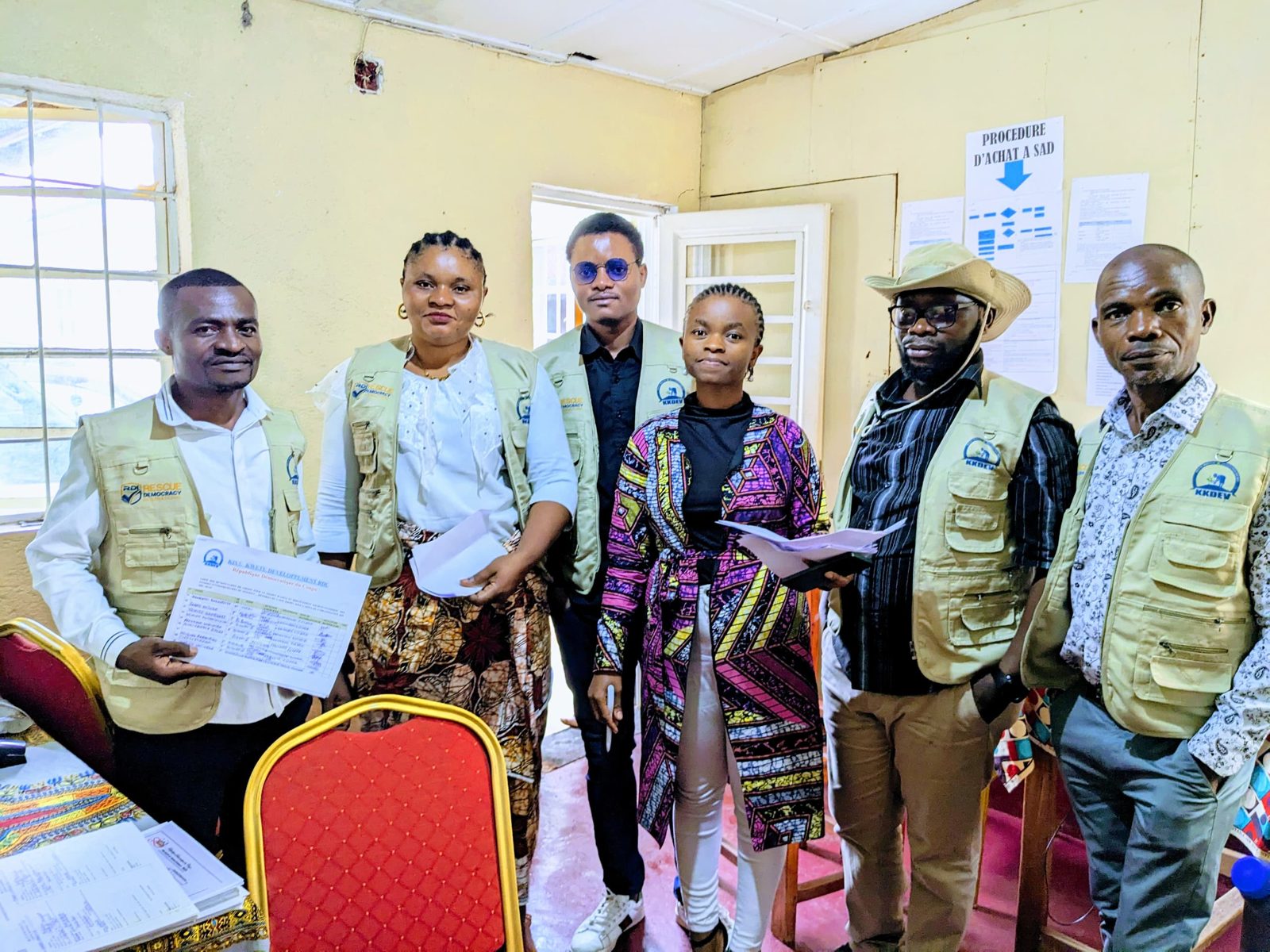 Six people in RDI and KKDEV vests holding a printed list